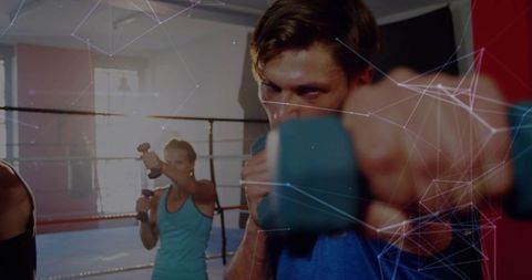 Dynamic boxing class punching with dumbbells in ring group fitness training session