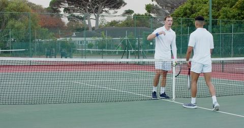 Tennis players fistbumping at net on outdoor hard court showing sportsmanship, camaraderie