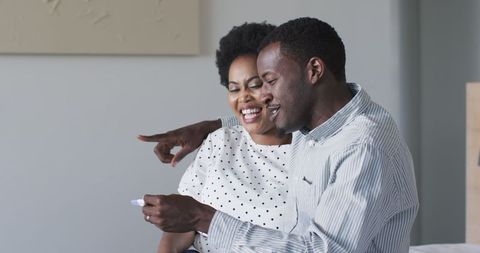Happy couple embracing positive pregnancy test result