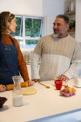 Couple baking together in cozy kitchen sharing smiles and kneading dough