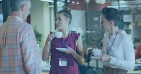 Professionals networking over coffee in modern glass office during meeting break