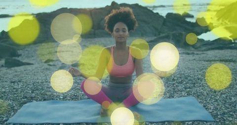 Woman Meditating on Pebble Beach Near Ocean at Sunset