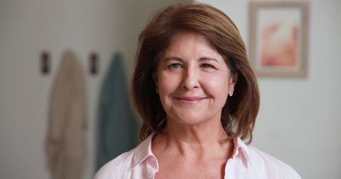 Elegant senior woman standing in warmly decorated home interior
