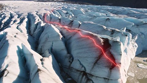 Neon red laser tracing deep glacier crevasse across blue ice ridge and meltwater