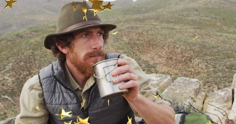 Bearded adventurer sipping coffee in rugged hillside