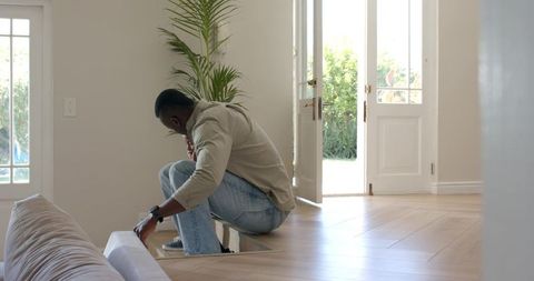African american man inspecting basement access in modern foyer with natural light