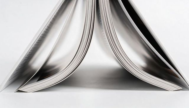 Glossy magazine pages forming symmetrical arches with reflective binding, catalog design