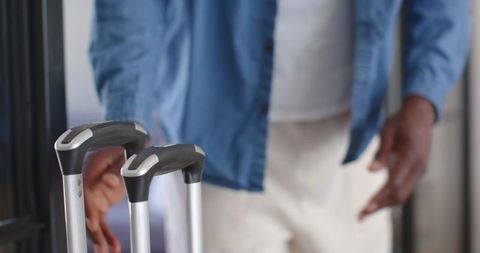 Mature traveler pulling telescopic suitcase handles through hotel corridor lobby