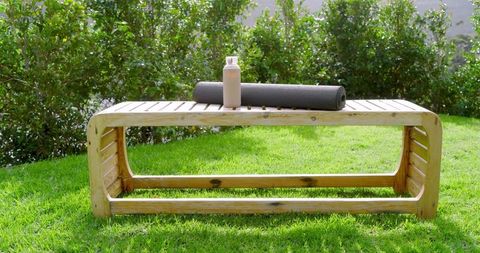 Wooden Bench with Fitness Mat and Water Bottle on Sunny Lawn