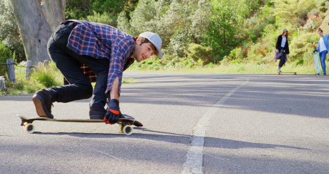 Young Man Skateboarding Downhill on Sunlit Road - Download Free Stock Images Pikwizard.com