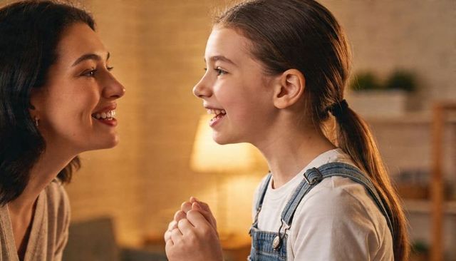 Mother and daughter sharing joyful conversation in cozy living room with warm lamp glow