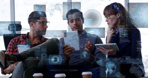 Diverse team collaborating with tablets and futuristic hud overlays in coworking space