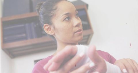 Caregiver adjusting wrist bandage on young woman in clinic hands securing gauze