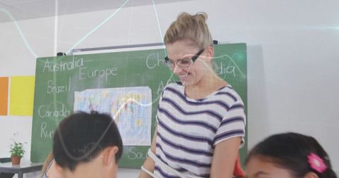 Teacher Assisting Students in Geography Lesson with Digital Maps