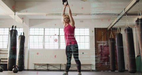 Woman performing kettlebell exercise in industrial gym ambiance
