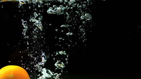 Orange and Water Interaction Displaying Splashes and Bubbles