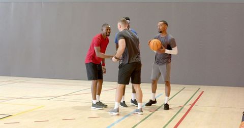 Men shaking hands on indoor basketball court showing team camaraderie and sportsmanship