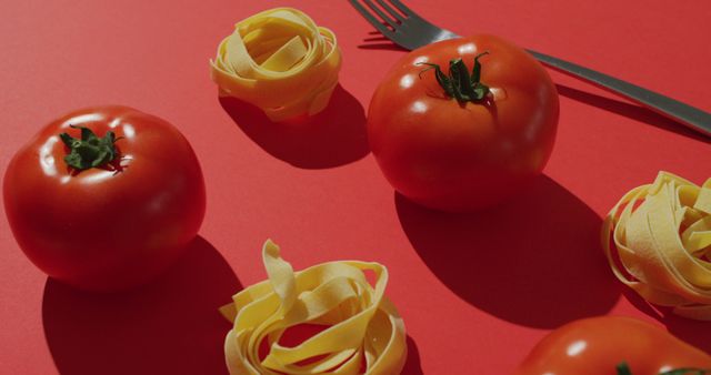 Image of fresh red tomatoes and pasta nests with fork on red background. fusion food, fresh vegetables and healthy eating concept.