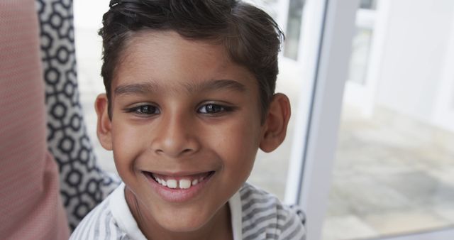 Smiling Young Boy With Dark Hair and Striped Shirt Looking at Camera - Download Free Stock Images Pikwizard.com