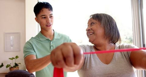 Male Physiotherapist Assisting Senior Woman with Resistance Band Exercise
