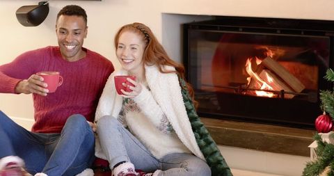 Cozy Couple Enjoying Hot Drinks by Fireplace During Christmas