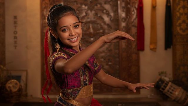 Young indian classical dancer in purple and gold costume performing graceful mudra pose