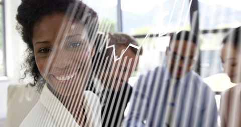 Smiling businesswoman presenting glass chart and analytics in collaborative team meeting