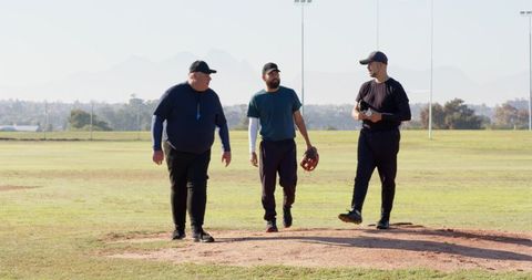 Coach Leading Two Players Walking on Pitcher's Mound During Baseball Practice