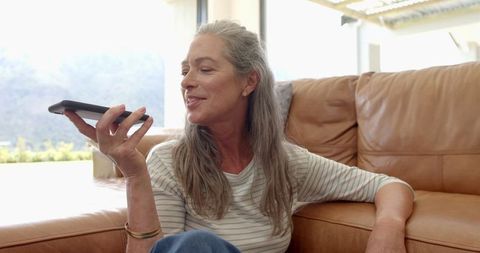 Mature Woman Engaged in Conversation on Smartphone on Couch
