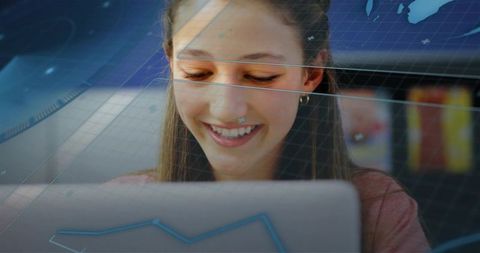Smiling teenage student studying on laptop with digital data overlays in coworking cafe