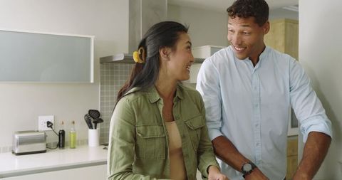 Smiling couple cooking together in bright modern kitchen preparing healthy meal and laughing