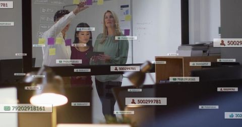 Business team collaborating at glass wall with sticky notes and digital data overlays