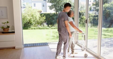 Healthcare professional assisting senior woman with mobility aid