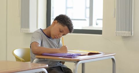 Focused Student Diligently Writing in Classroom