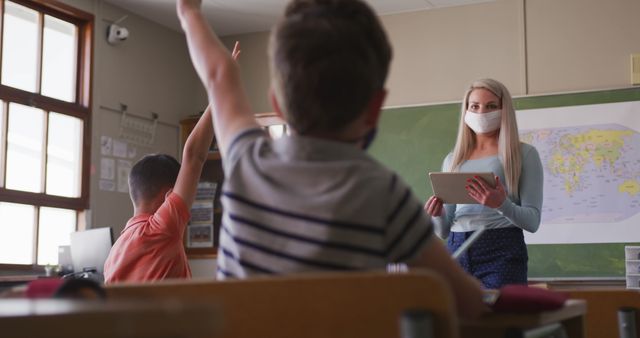 Primary School Teacher Wearing Mask Engaging with Students in Classroom - Download Free Stock Images Pikwizard.com