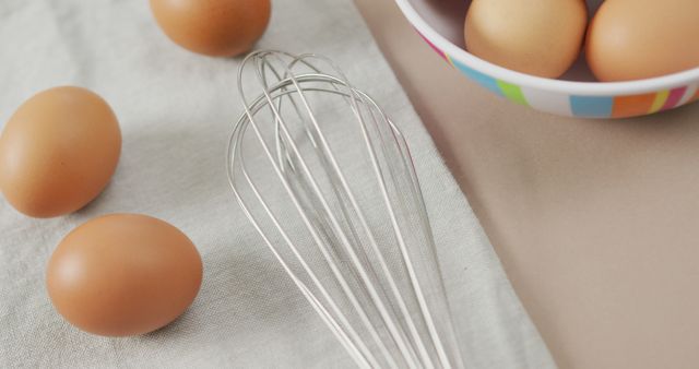 Image of overhead view of eggs and egg whisk on rustic cloth on beige background. fusion food, baking, eggs and easter concept.