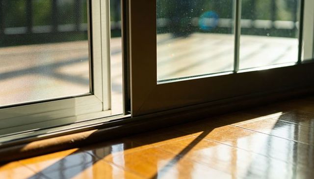 Sunlight streaming through sliding glass door casting shadows on parquet floor