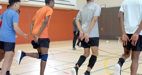 Multiethnic teen athletes jogging indoor gym volleyball drill wearing knee pads
