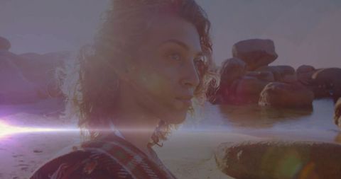 Woman Embracing Tranquil Sunset on Rocky Shoreline