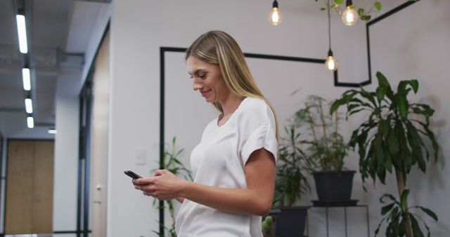 Portrait of caucasian woman smiling while using smartphone at office. business, professionalism and office concept