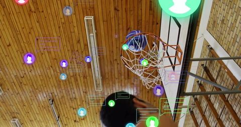 Basketball player shooting through hoop with social media chat icon overlay in wooden gym