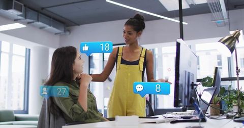Young Female Colleagues Collaborating at Modern Desk with Social Media Notifications