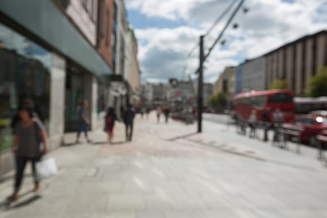 This image captures the essence of a busy city street with pedestrians walking on a sunny day. The blurred effect adds a sense of motion and activity, making it ideal for use in projects related to urban life, transportation, and daily routines. It can be used in websites, blogs, and advertisements focusing on city living, travel, and lifestyle themes.