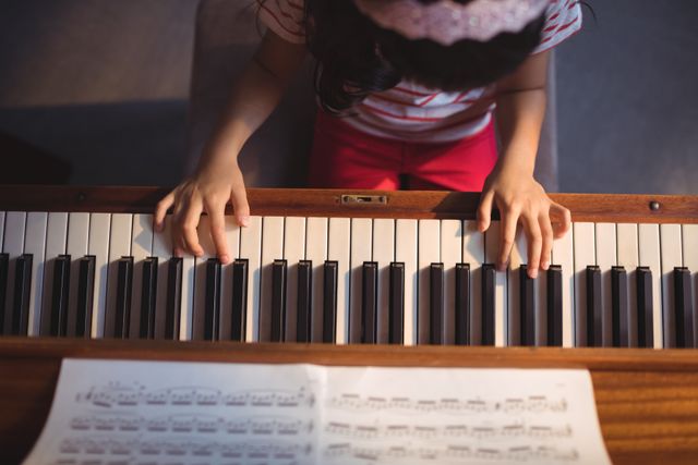 Overhead view of girl practicing piano in classroom at music school