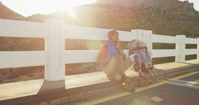 Tired Backpacker Resting on Mountain Roadside in Morning Light - Download Free Stock Images Pikwizard.com