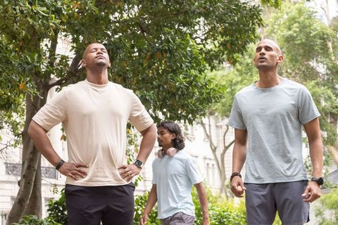 Breathing deeply in urban greenspace with diverse friends stretching under canopy