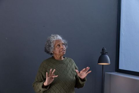 Senior woman gesturing in modern minimalist interior with lamp