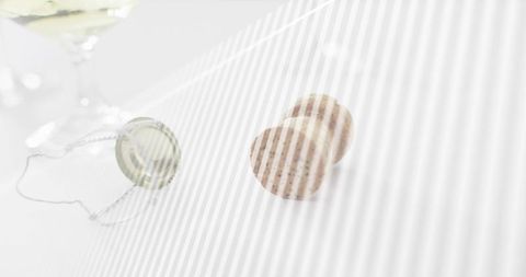 Speckled champagne corks resting on white tabletop with muselet wire and cap, minimalist