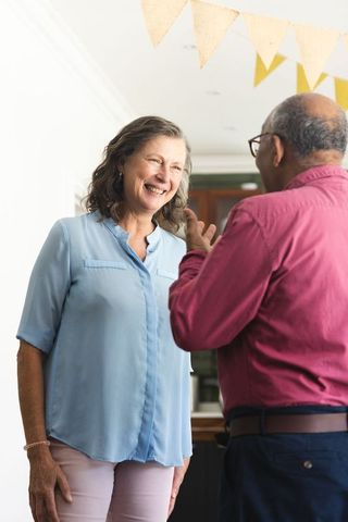 Mature couple smiling and chatting at home celebration with bunting flags and warm light