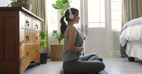 Asian Woman Meditating at Home with Headphones